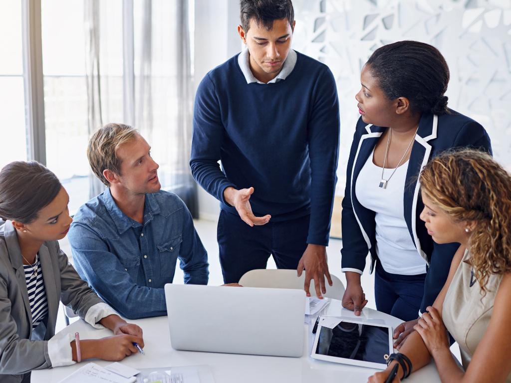 A group of professionals gathered around a laptop on a table.