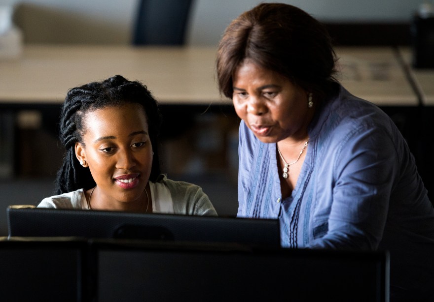 A mentor and her apprentice at a computer viewing apprentice tracking data.