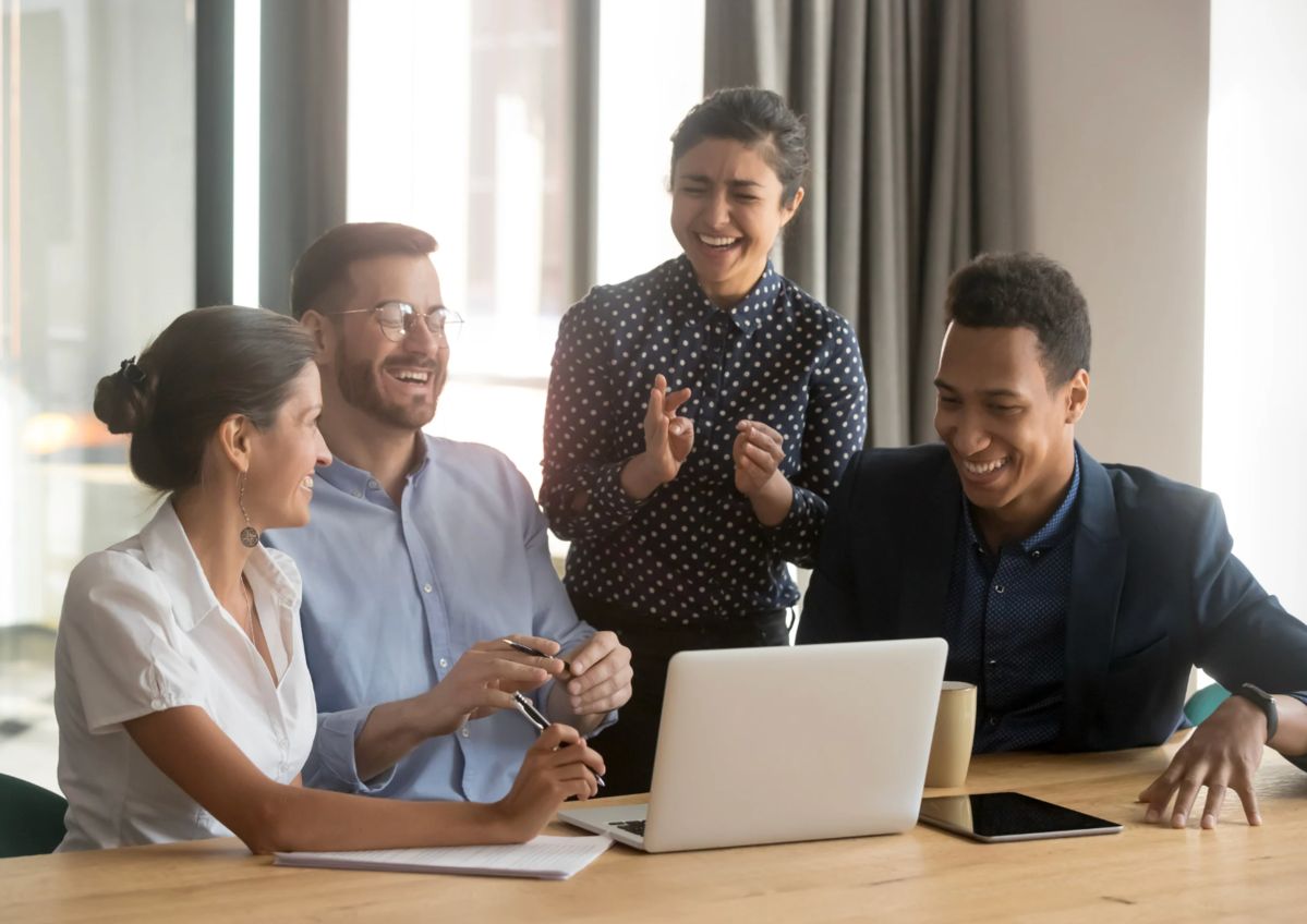 People laughing around a laptop.