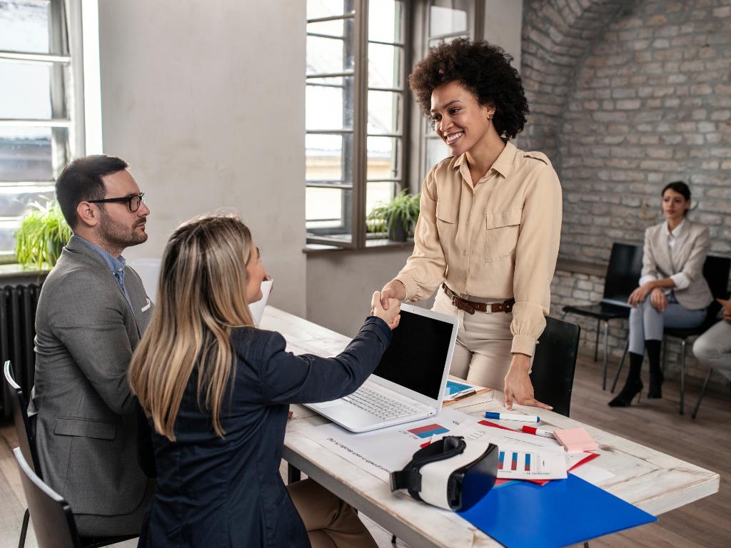2 Two women shaking hands in an interview room.