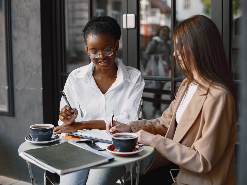 5 Two women sitting at a small table working out apprenticeship ROI.
