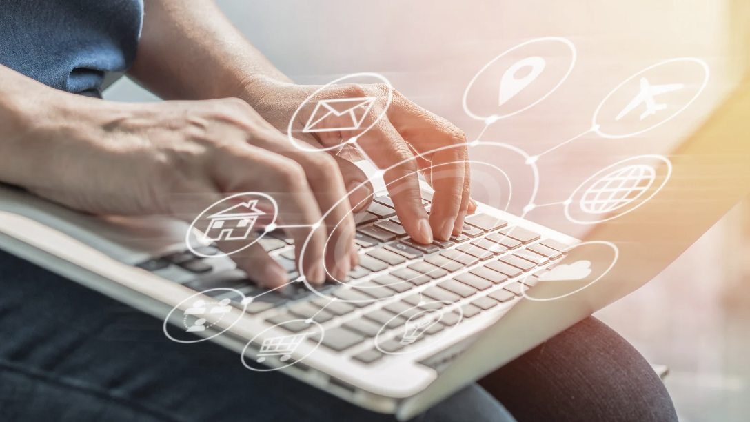 Hands on a laptop keyboard with a selection of apps in a circular dial superimposed over the image